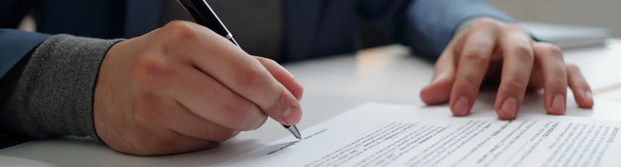 man-signing-contract-in-office-with-male-hand-hold
